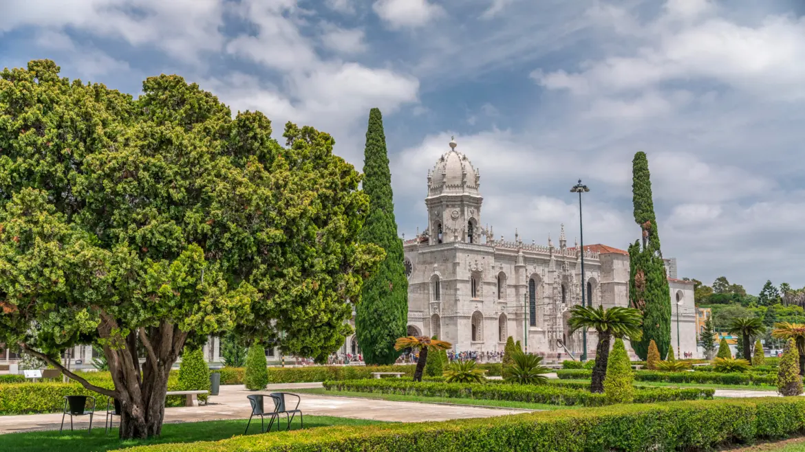 Exterior of Jerónimos Monastery seen from the gardens in Belém Lisbon with trees and Manueline bell tower