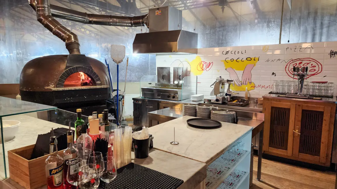 Traditional wood-fired pizza oven inside Mercato Centrale in Florence’s San Lorenzo district, with flames and fresh pizza in the bustling market