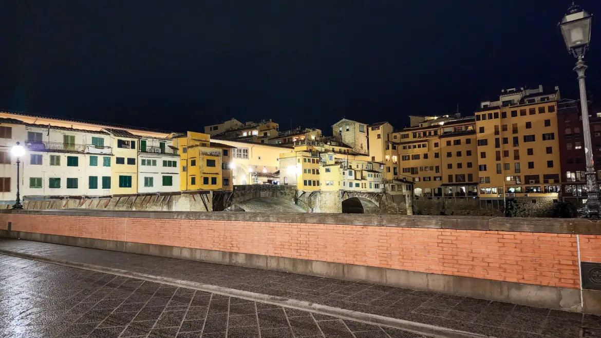 Ponte Vecchio illuminated at night over the Arno River in Florence, with the medieval bridge glowing against the dark sky on a farewell evening