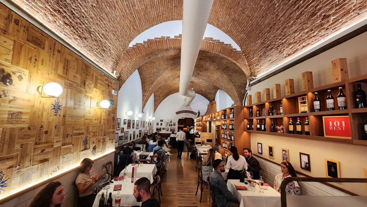 Warm interior of Trattoria Dall’Oste in Florence with exposed brick walls, rustic wooden tables, and wine displays