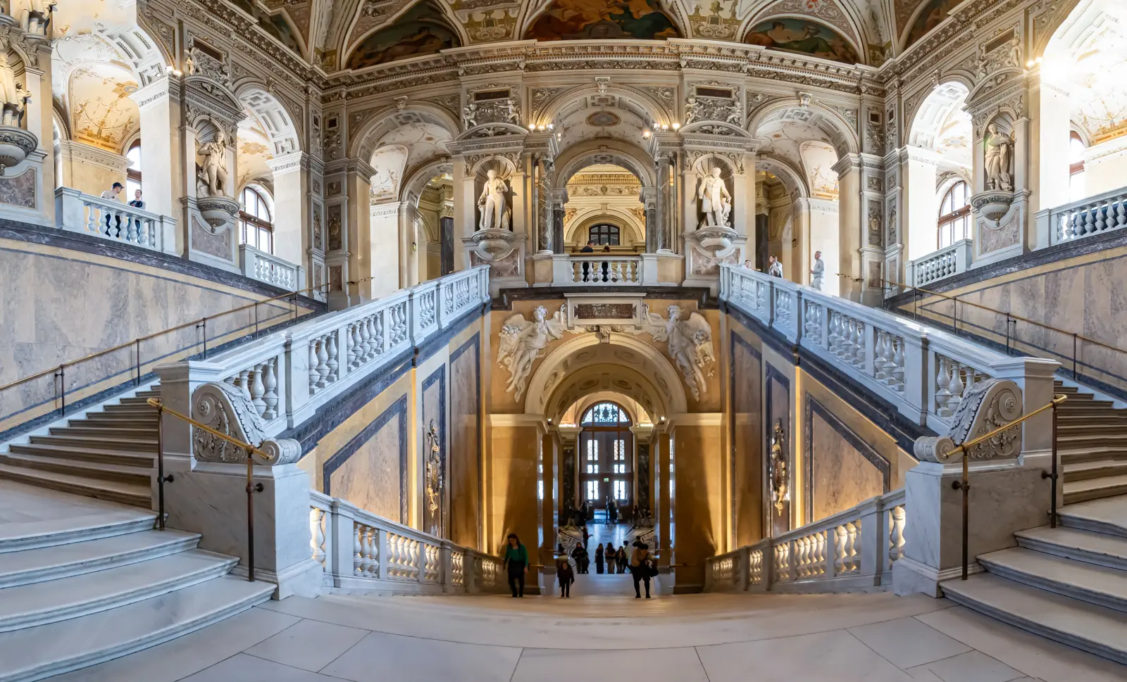 The sweeping grand staircase of the Naturhistorisches Museum Wien featuring marble steps, ornate detailing, and richly decorated ceilings