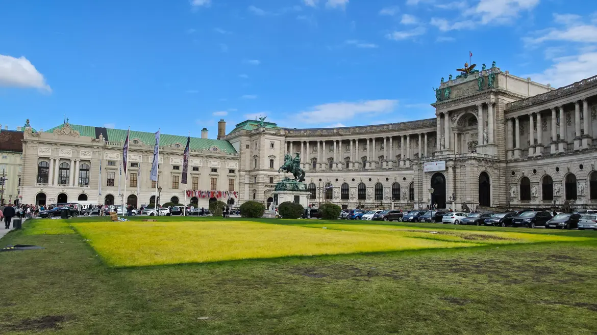 The monumental curved façade of the Neue Burg at the Hofburg Palace complex overlooking the green lawns of Heldenplatz in Vienna