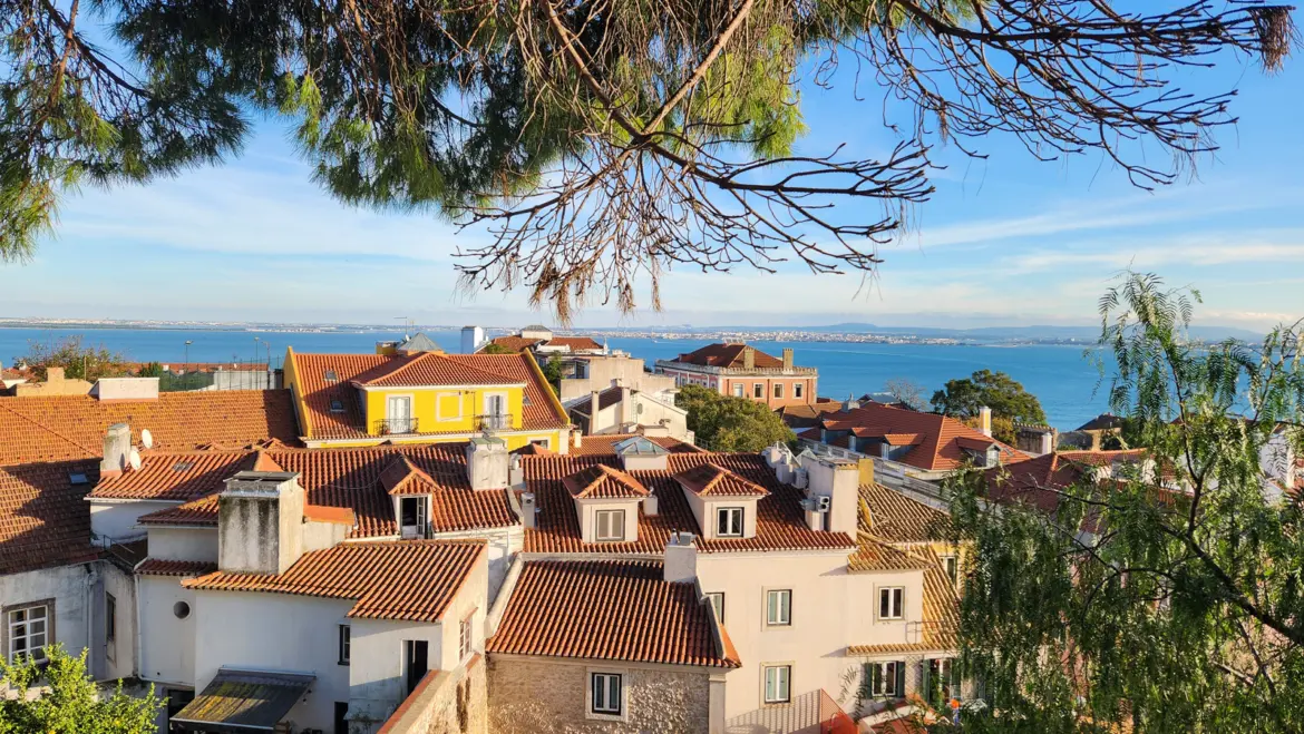 Terracotta rooftops of Lisbon with the Tagus River in the background on a sunny day