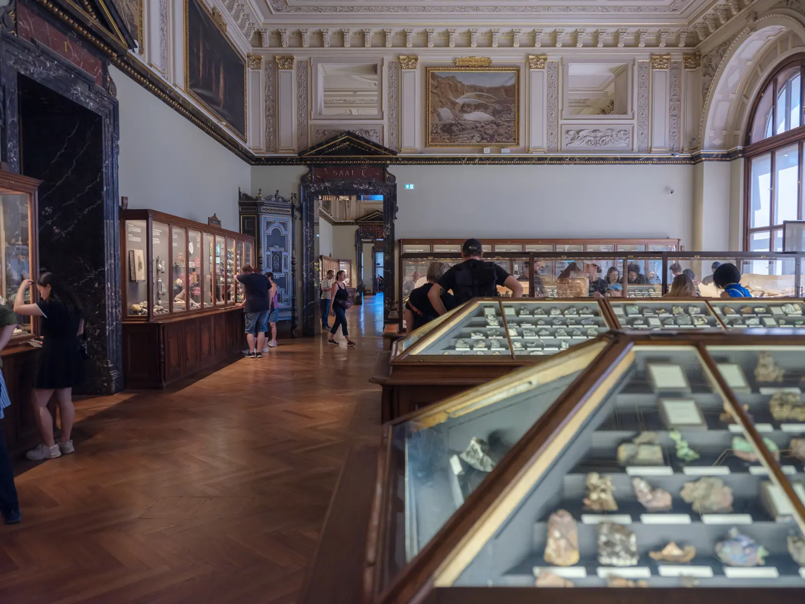 Visitors exploring the mineral and gemstone hall at the Naturhistorisches Museum Wien featuring raw and polished specimens