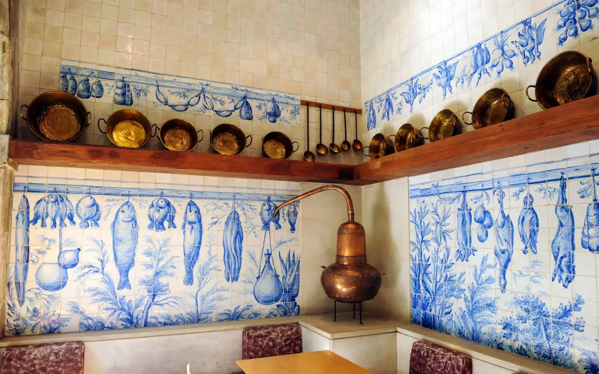 Blue-and-white kitchen azulejos with copper pots at the National Tile Museum in Lisbon depicting fish and food scenes