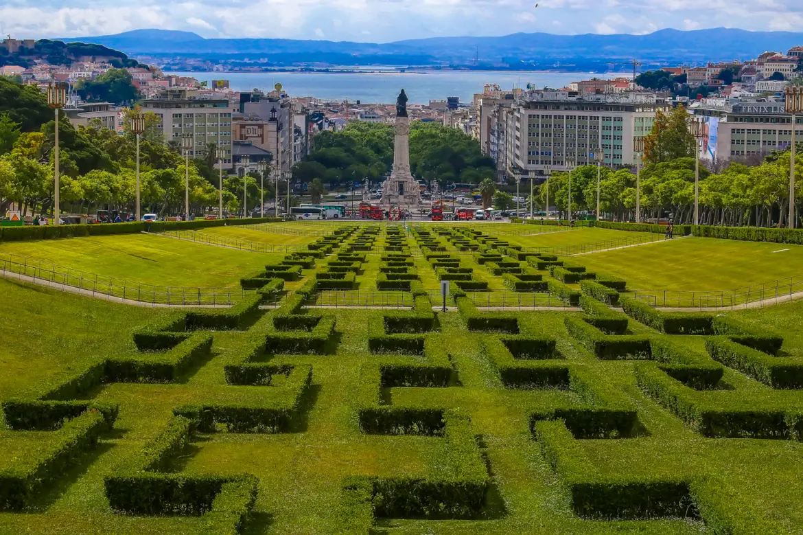 Panoramic view of Parque Eduardo VII in Lisbon showing geometric box hedges stretching toward Marquês de Pombal and the Tagus River