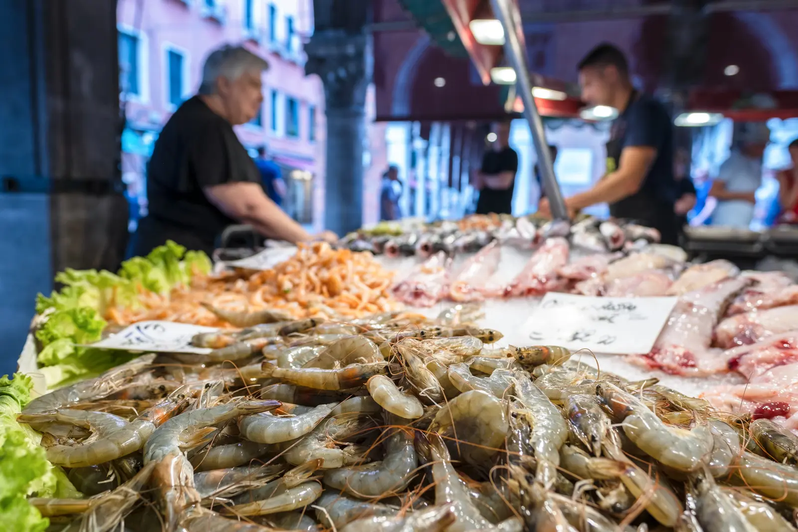 Fresh fish on display at the Pescheria di Rialto in Venice with vendors and shoppers