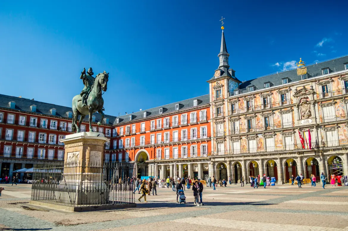 Plaza Mayor in Madrid with the equestrian statue of Philip III and terracotta arcaded façades on a sunny day