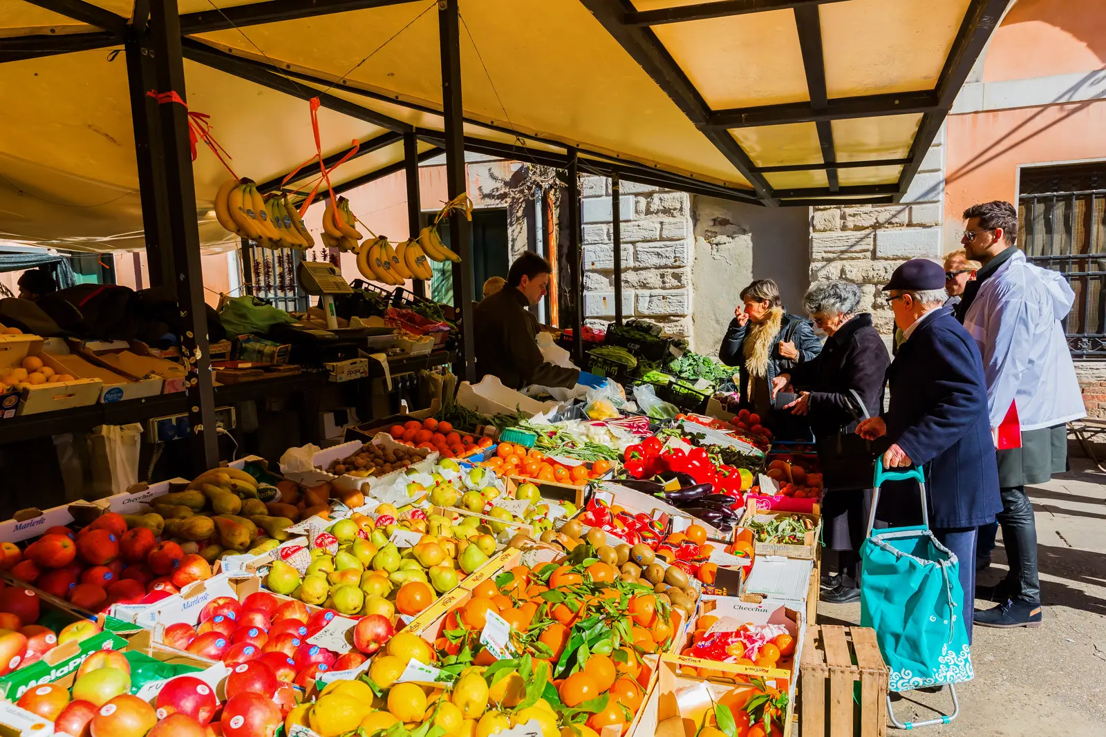 Fresh produce stalls at the Rialto Market in Venice, Italy, with colorful fruits and vegetables