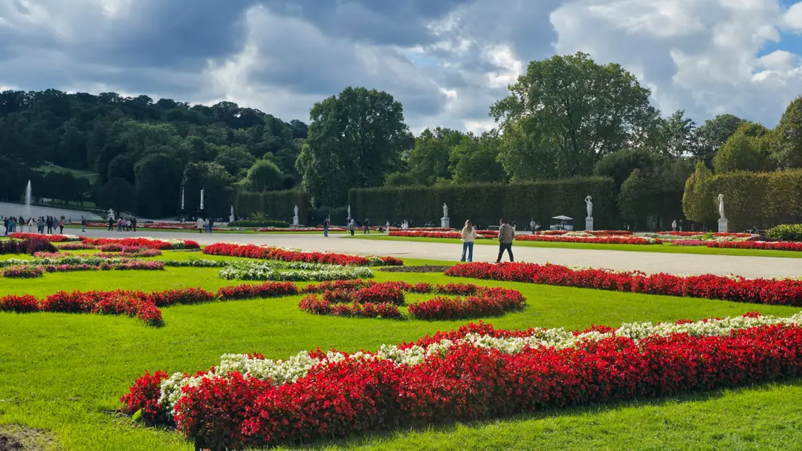 Visitors enjoying leisurely walks through the Great Parterre at Schönbrunn Gardens in Vienna, surrounded by flowers, sculptures, and greenery