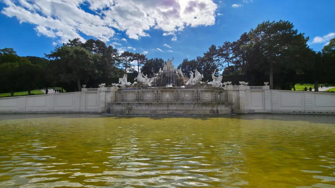 The Neptune Fountain at the end of the Great Parterre in Schönbrunn Gardens, Vienna, with water cascading beneath sculpted mythological figures
