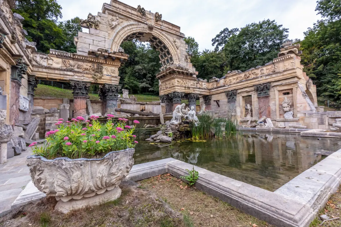 The Roman Ruin at Schönbrunn Palace in Vienna, an 18th-century garden folly with broken arches, weathered columns, and a sculptural fountain representing the Danube and Enns rivers