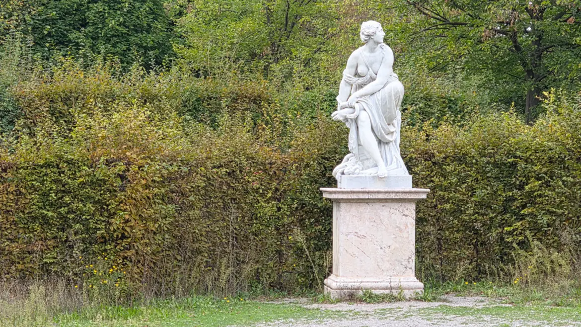 Classical statue among greenery in Schönbrunn Palace gardens Vienna, one of many sculptures that line the garden pathways