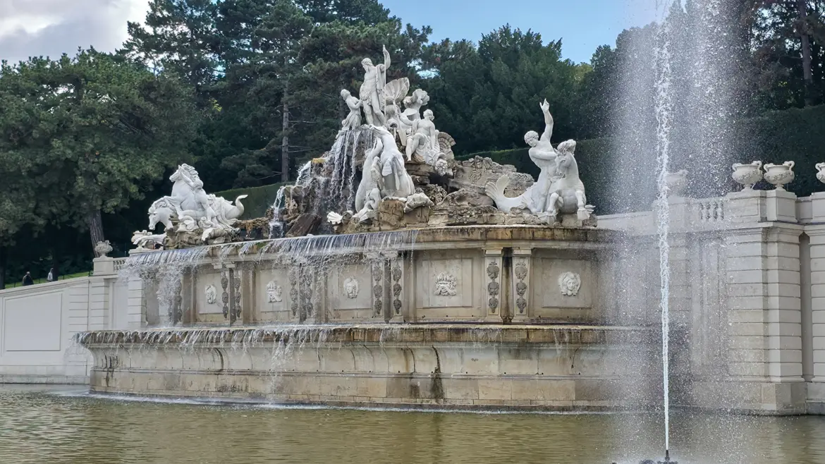 Close-up of the Neptune sculpture at the Neptune Fountain in Schönbrunn Palace gardens, depicting the Roman sea god in dramatic Baroque style