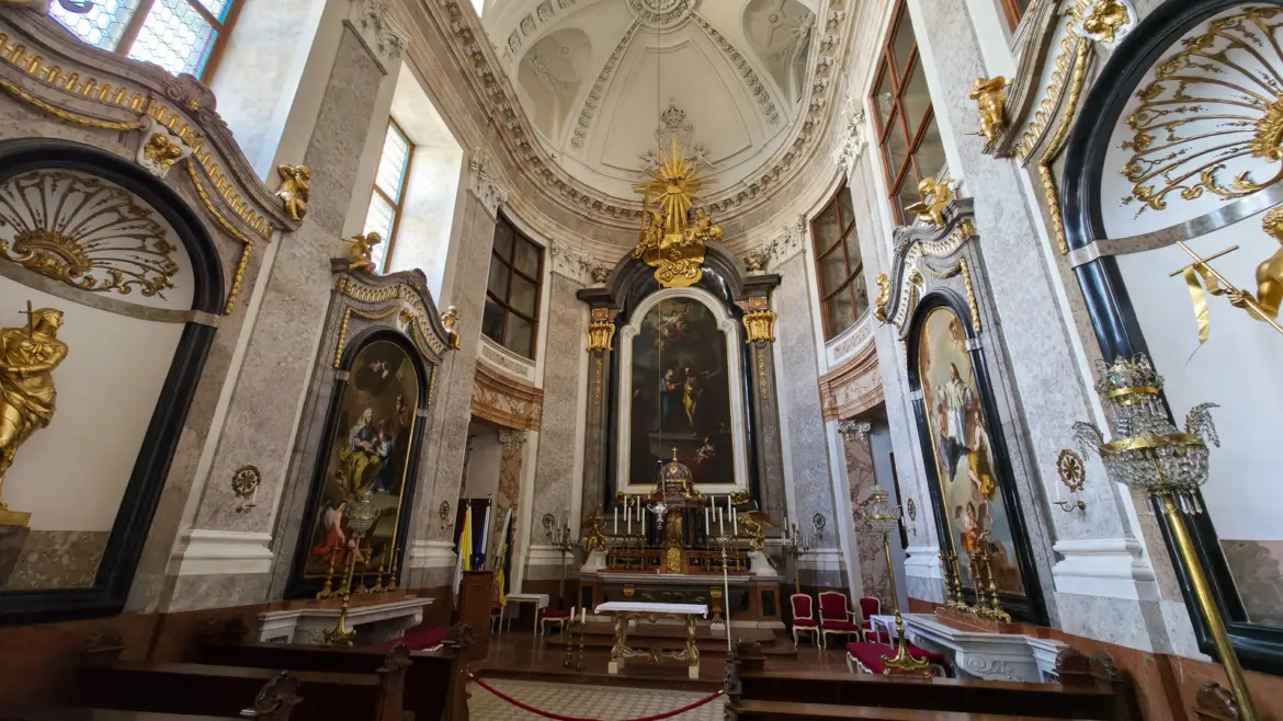 The Schlosskapelle (Palace Chapel) inside Schönbrunn Palace in Vienna, a Baroque chapel with gilded altarpiece, marble columns, and religious paintings once used by the Habsburg court