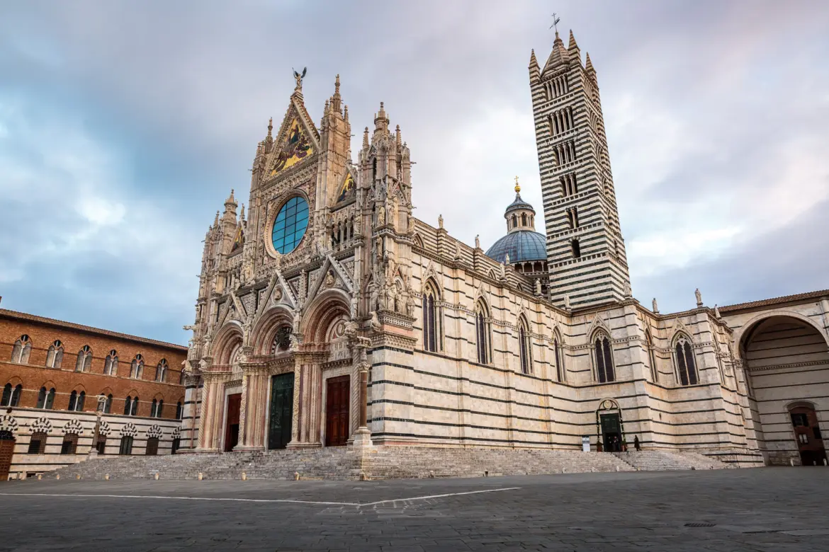 The striking Gothic façade of Siena Cathedral (Duomo di Siena), a masterpiece of Italian Gothic architecture with intricate sculptures and dramatic black-and-white marble