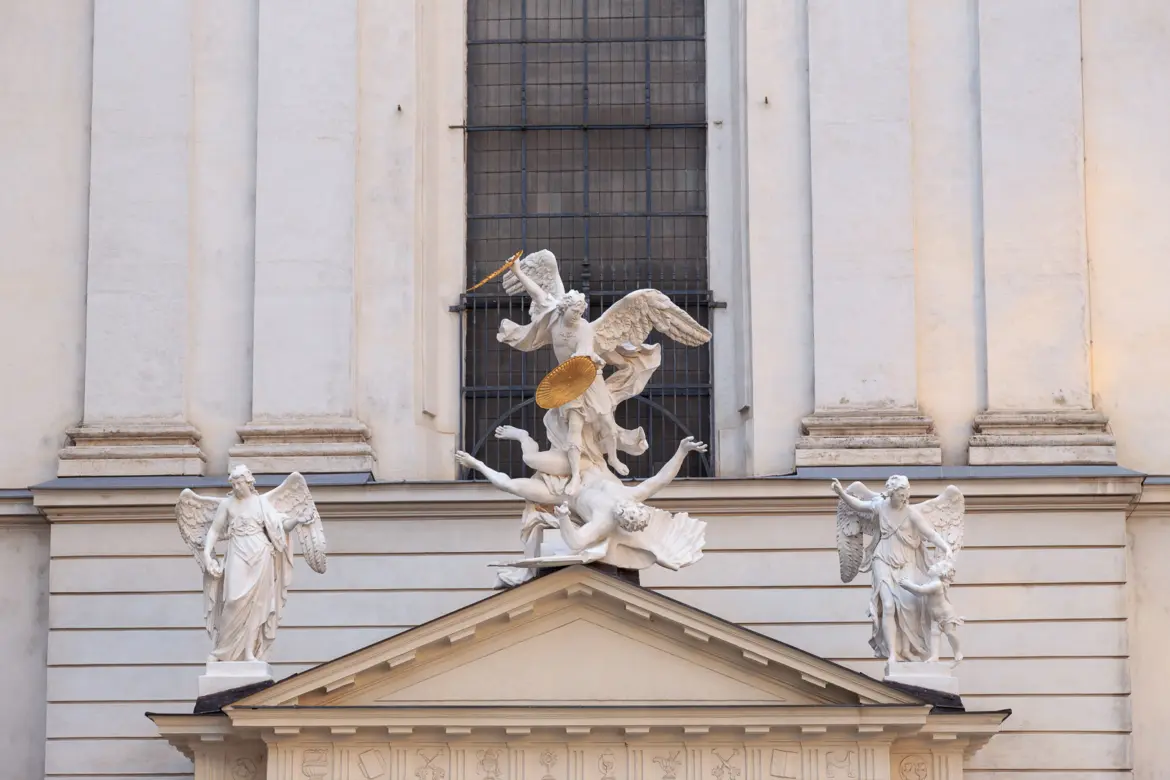 Baroque sculpture of St. Michael slaying Lucifer above the entrance of St. Michael’s Church in Vienna, created by Lorenzo Mattielli in 1725