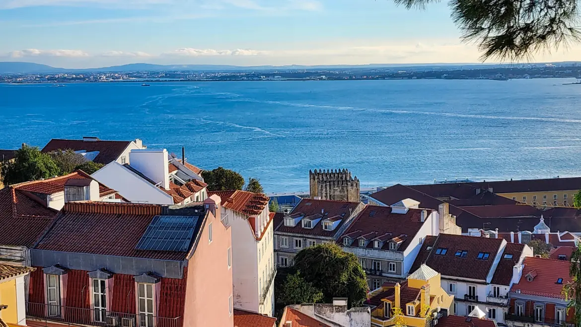 Tagus River stretching wide beyond terracotta rooftops of Lisbon seen from an elevated viewpoint