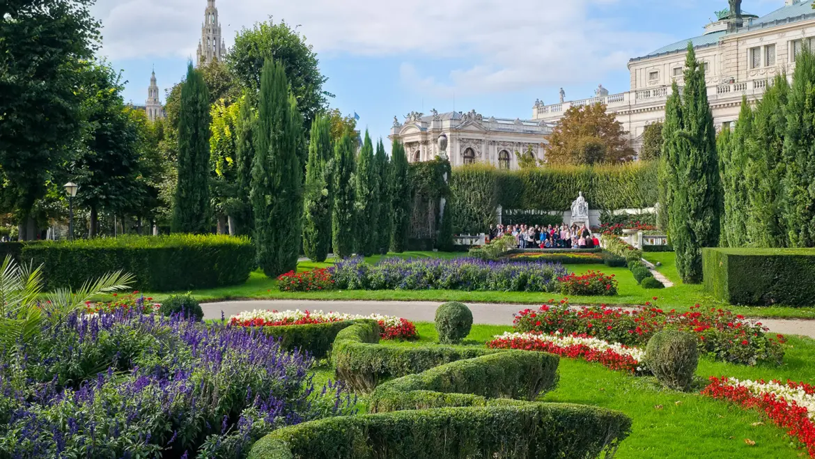 The Sisi monument surrounded by colorful flowers, manicured hedges, and cypress trees in Volksgarten, one of Vienna’s most beautiful historic gardens near Heldenplatz