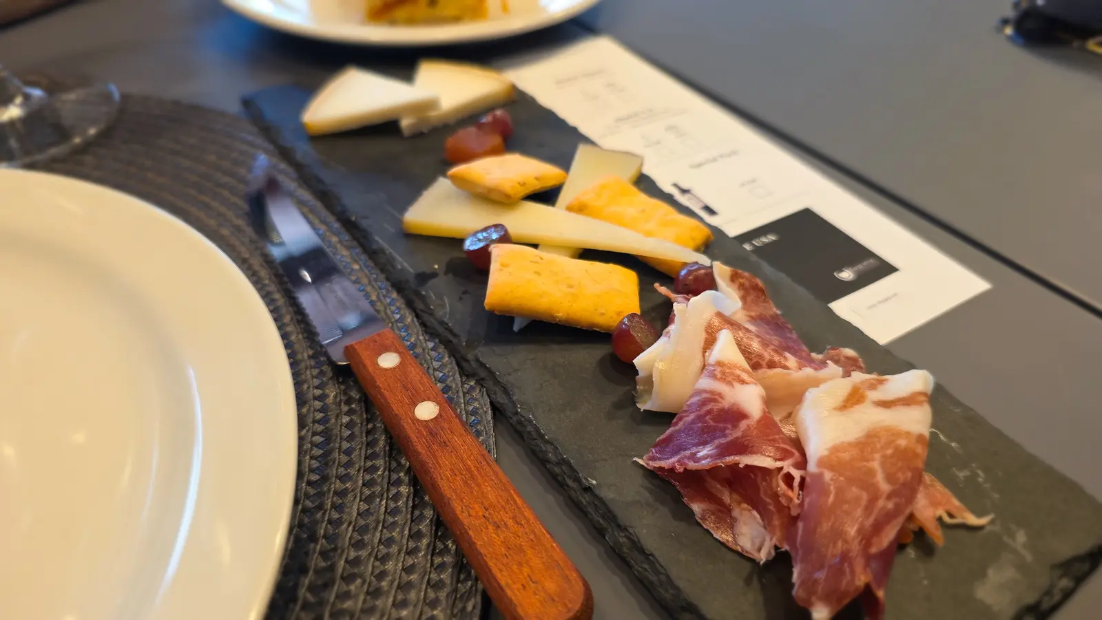 Homemade food pairing at Abadal Winery featuring local cheeses, crusty bread, cured meats, estate honey, and olive oil alongside glasses of Picapoll and Mandó wines