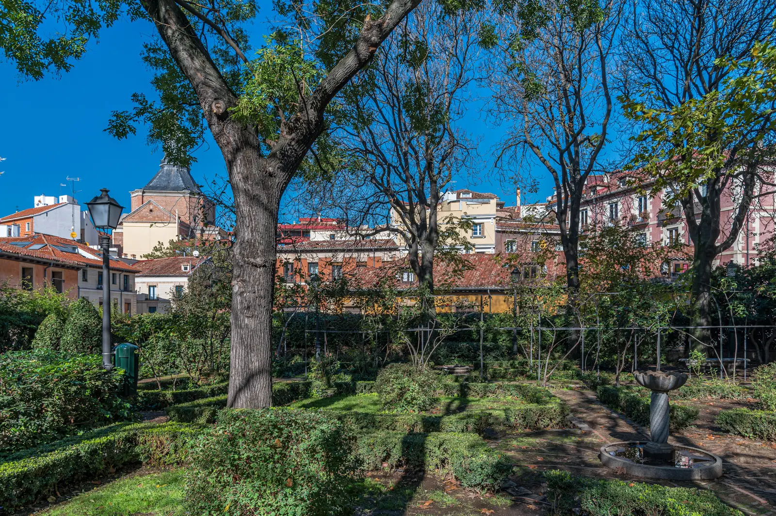 Central stone well surrounded by hedges and roses in the Anglona Garden in La Latina Madrid