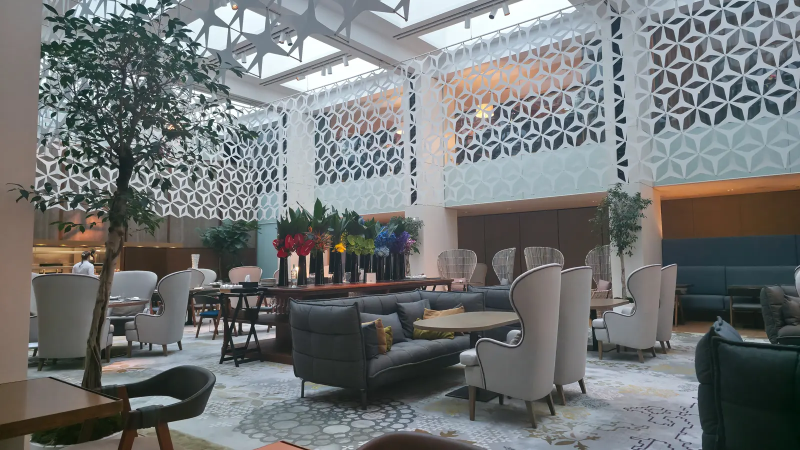 The elegant interior of Blanc restaurant at the Mandarin Oriental, Barcelona, featuring exquisite floral arrangements with tall orchids and lush hydrangeas anchoring the minimalist white dining space