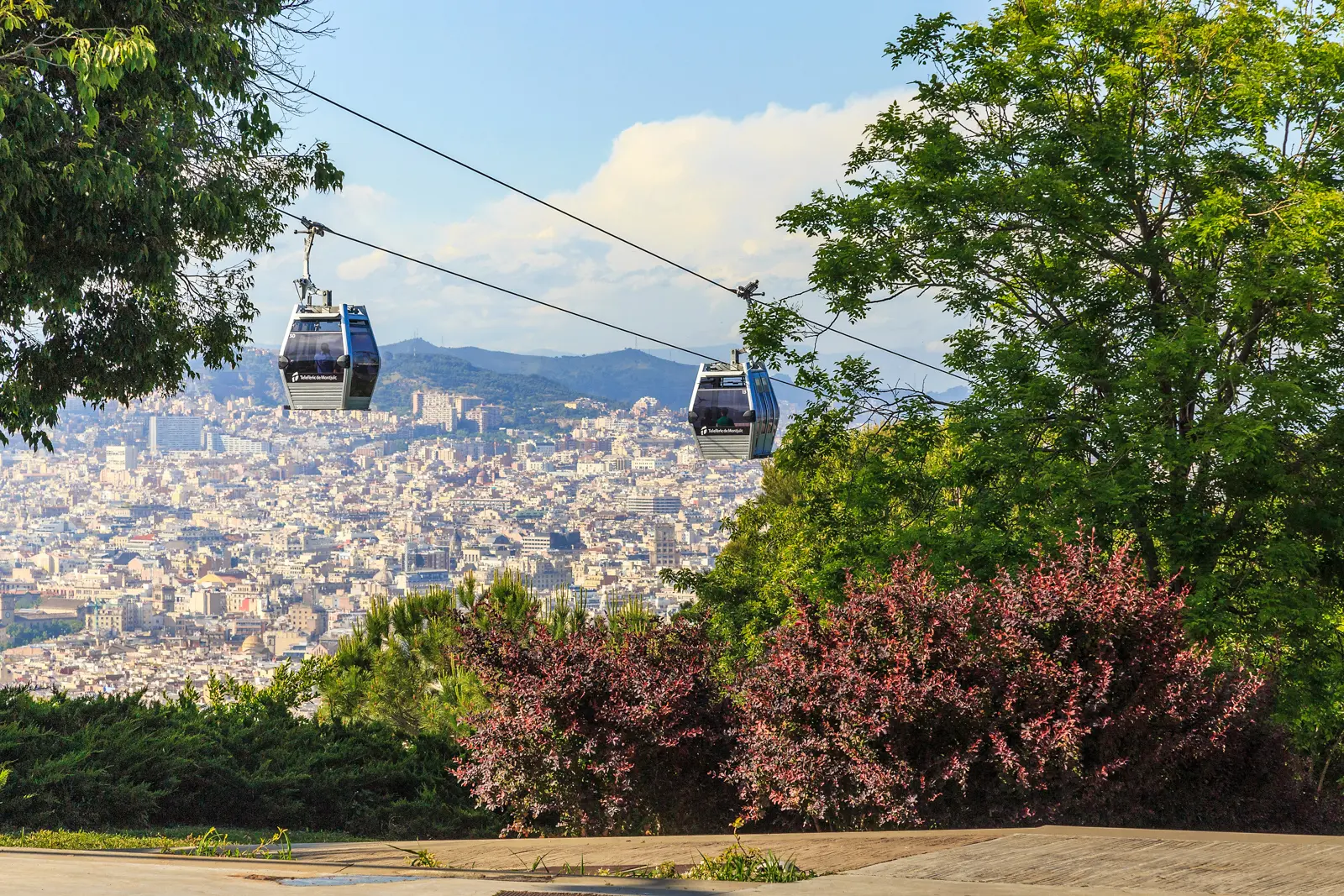 The Telefèric de Montjuïc cable car crossing above Barcelona with panoramic views of Port Vell, the coastline, and Montjuïc Castle — a key scene in Dan Brown's Origin