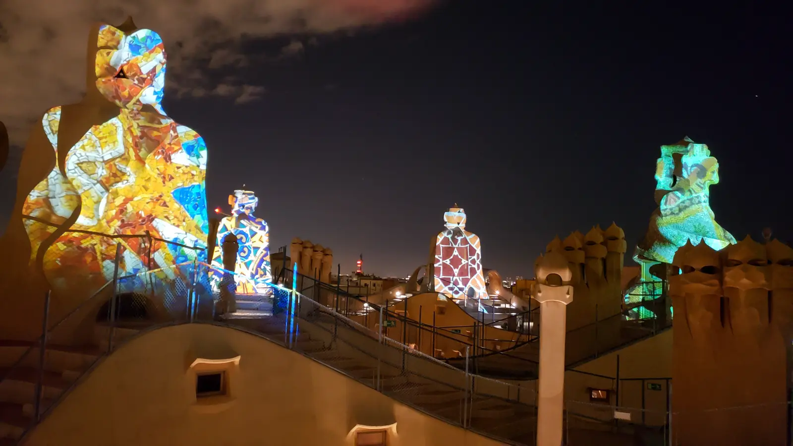 La Pedrera (Casa Milà) Night Experience in Barcelona, with the rooftop glowing golden under dramatic evening lighting and the stone warrior chimneys silhouetted against the Barcelona skyline