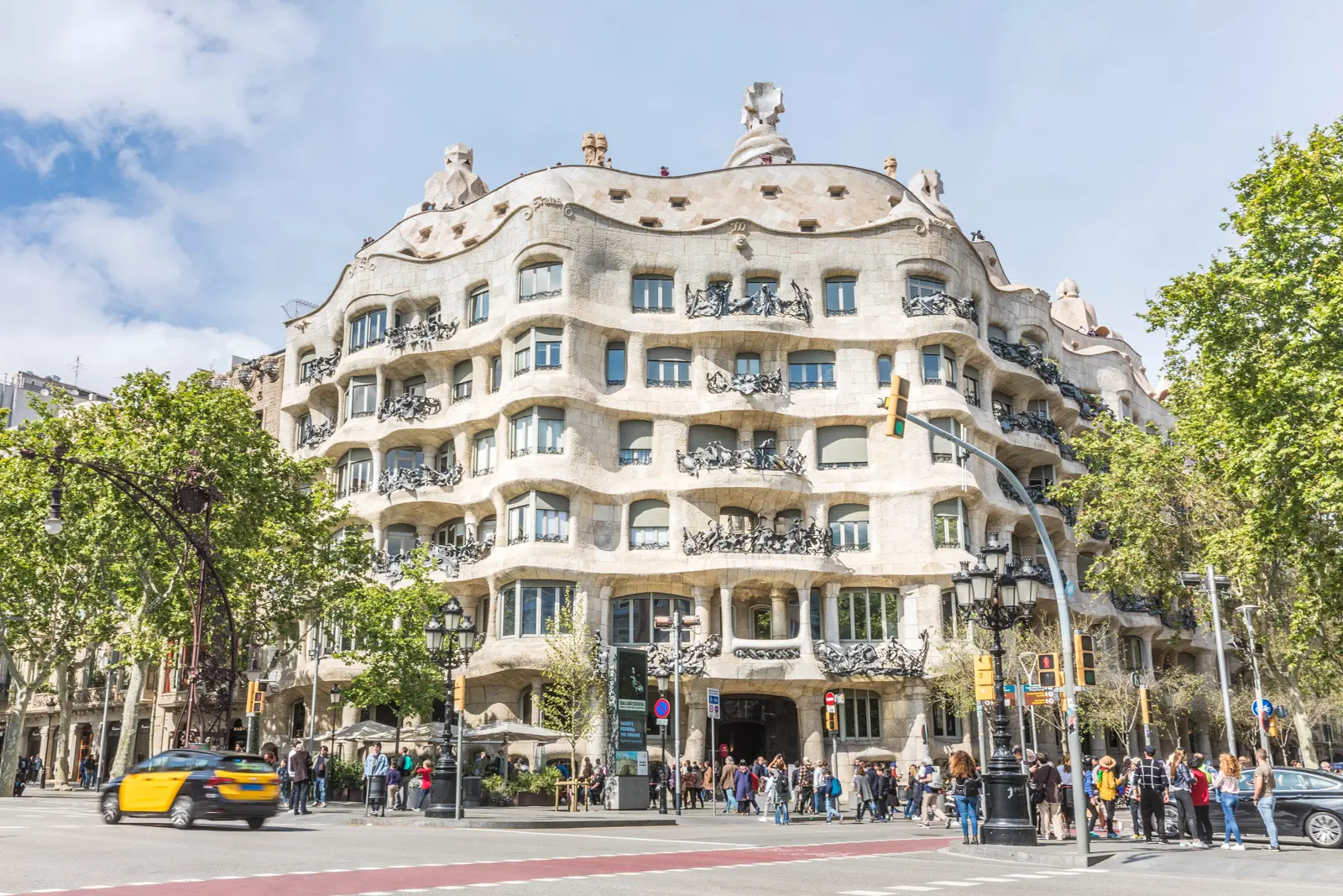 The rooftop of La Pedrera (Casa Milà) in Barcelona, with Gaudí's iconic warrior-like chimneys twisting toward the sky against the Mediterranean blue — a dreamscape of curves, stone, and shadow