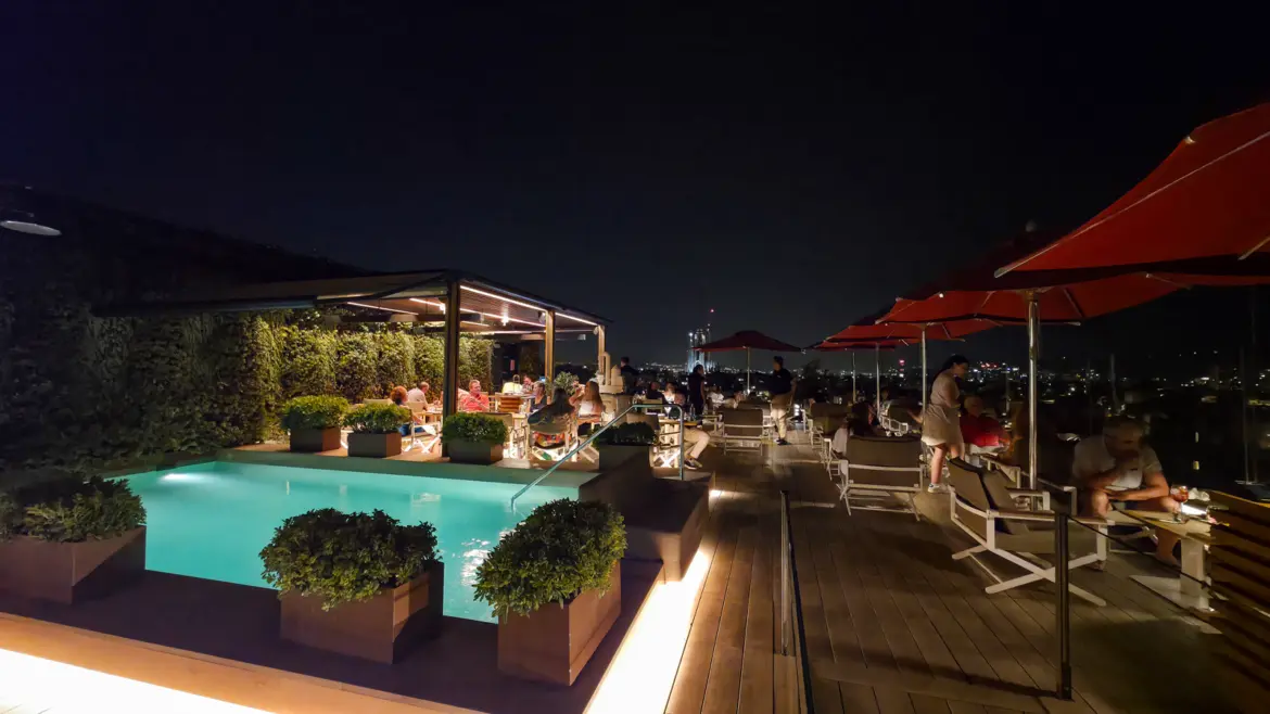 La Dolce Vitae rooftop terrace at the Majestic Hotel Barcelona at night, with ambient lighting, the illuminated Barcelona skyline, and the glow of Passeig de Gràcia below