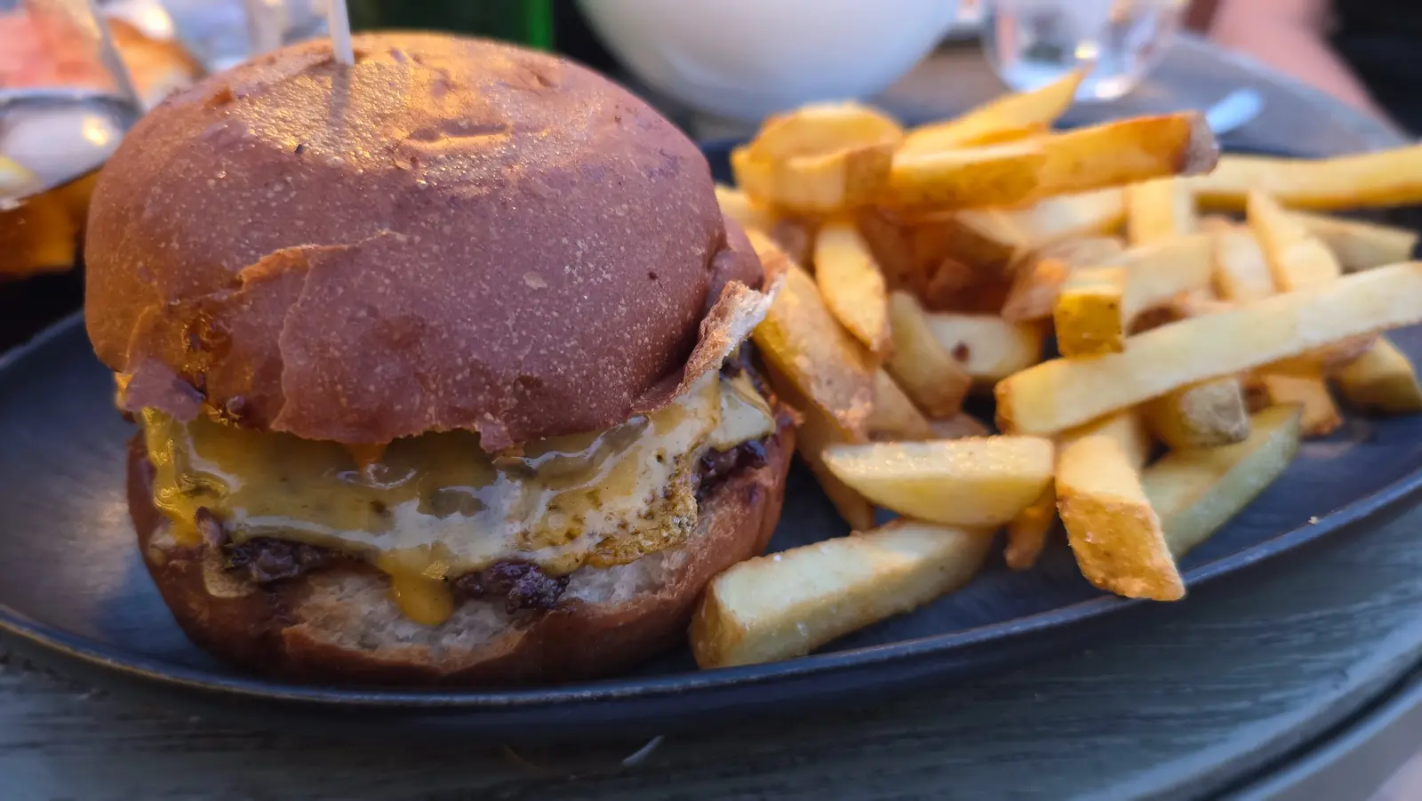 Organic beef smash burger with melted cheese, pickles, and Majestic sauce at La Dolce Vitae rooftop, Majestic Hotel Barcelona — caramelized edges, gooey cheese, and a tangy house sauce