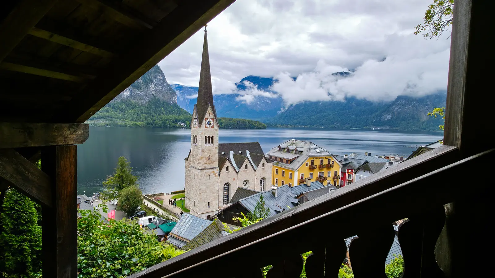 Elevated view of Hallstatt featuring the Evangelische Pfarrkirche at the center of the village, with Lake Hallstatt and mountains in the background