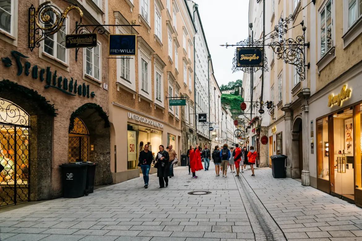 Narrow historic Getreidegasse street with wrought-iron guild signs hanging over medieval townhouses in Salzburg