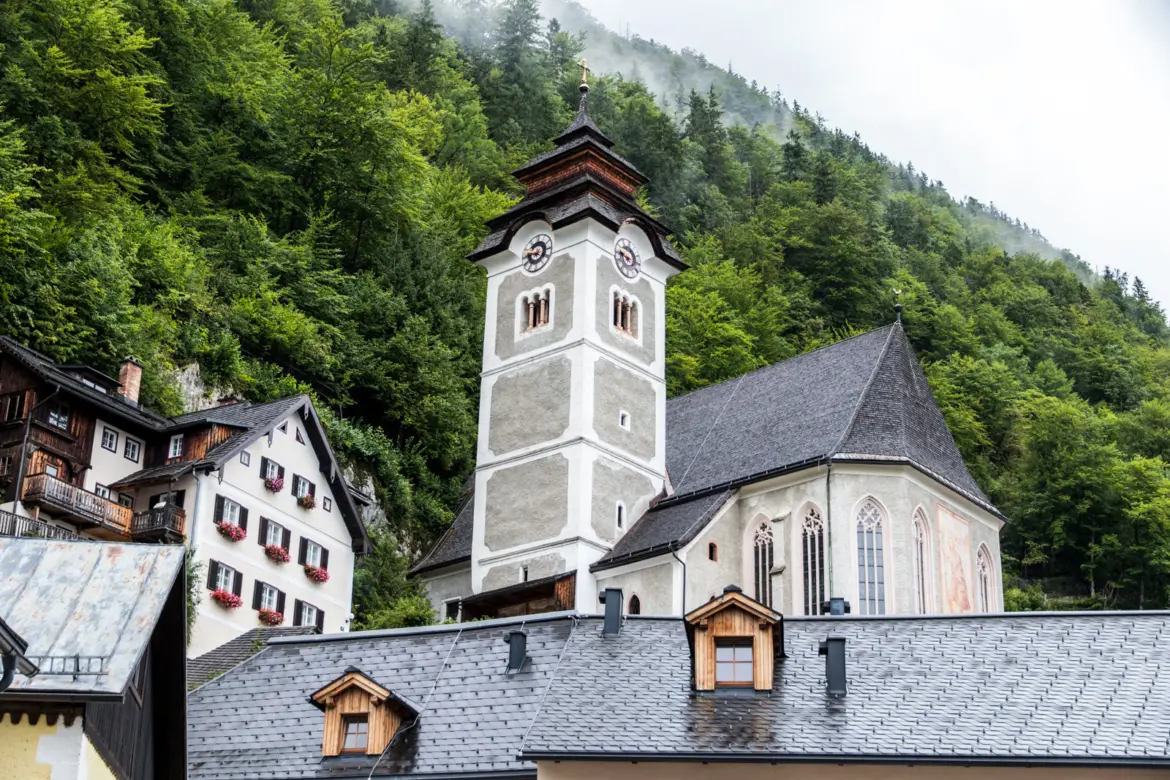 Pfarrkirche Mariä Himmelfahrt on a misty hillside in Hallstatt, overlooking the village on a rainy day