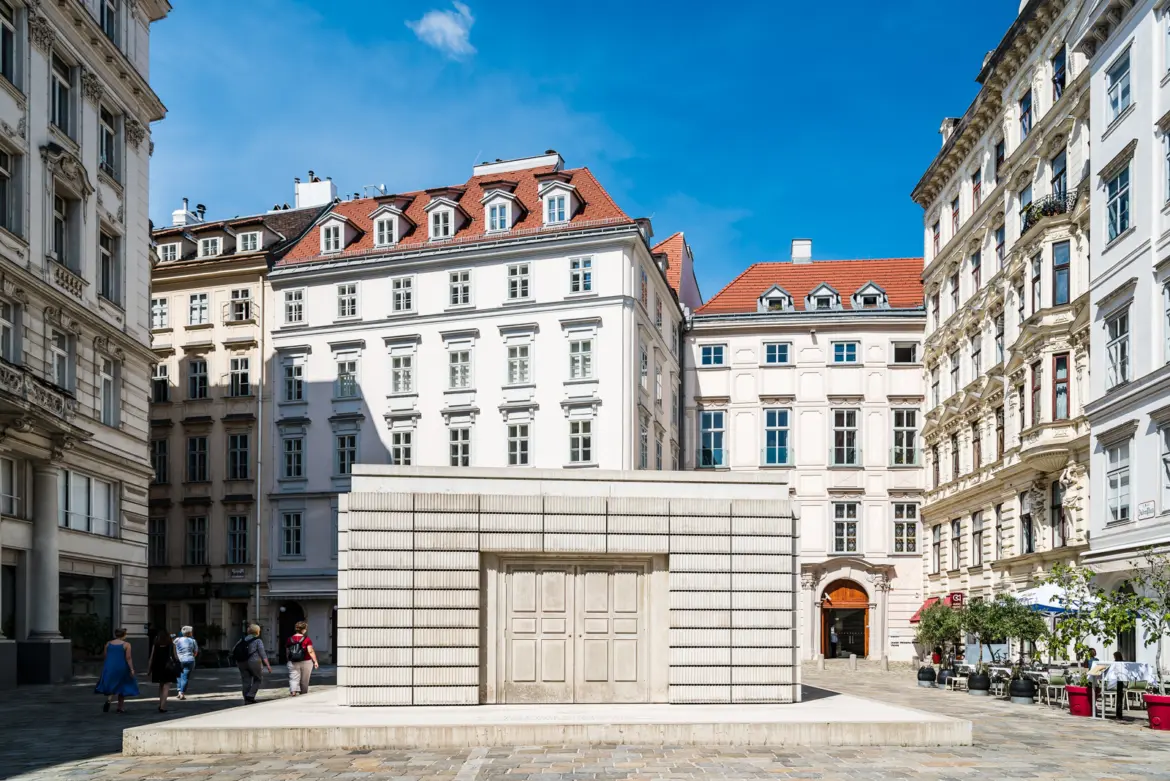 The Holocaust Memorial by Rachel Whiteread in Judenplatz Vienna, a monolithic concrete structure surrounded by historic facades under a clear blue sky