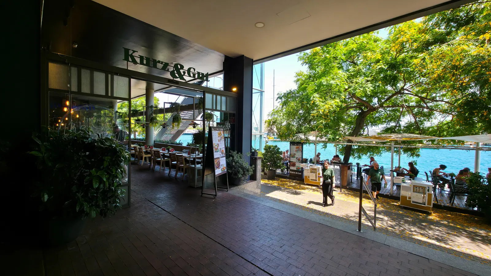 Outdoor seating area at Kurz & Gut Maremagnum Barcelona captured in warm afternoon light with harbour views