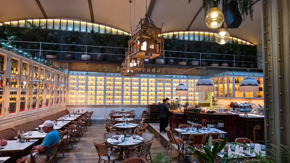 La Parada at El Nacional in Barcelona — the casual delicatessen corner inside the iconic 1889 multi-restaurant venue on Passeig de Gràcia, with warm afternoon light through iron beams and glass