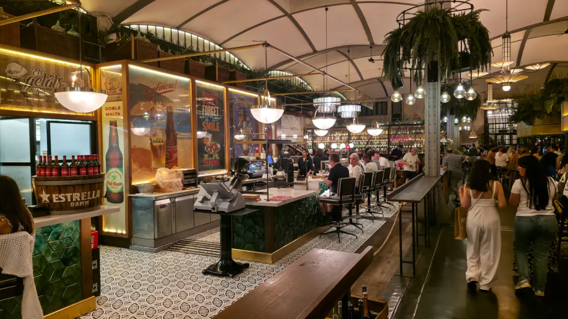 La Taperia at El Nacional in Barcelona — the lively tapas corner of the iconic 1889 multi-restaurant venue on Passeig de Gràcia, with green-tiled walls, brass fixtures, and botanical accents