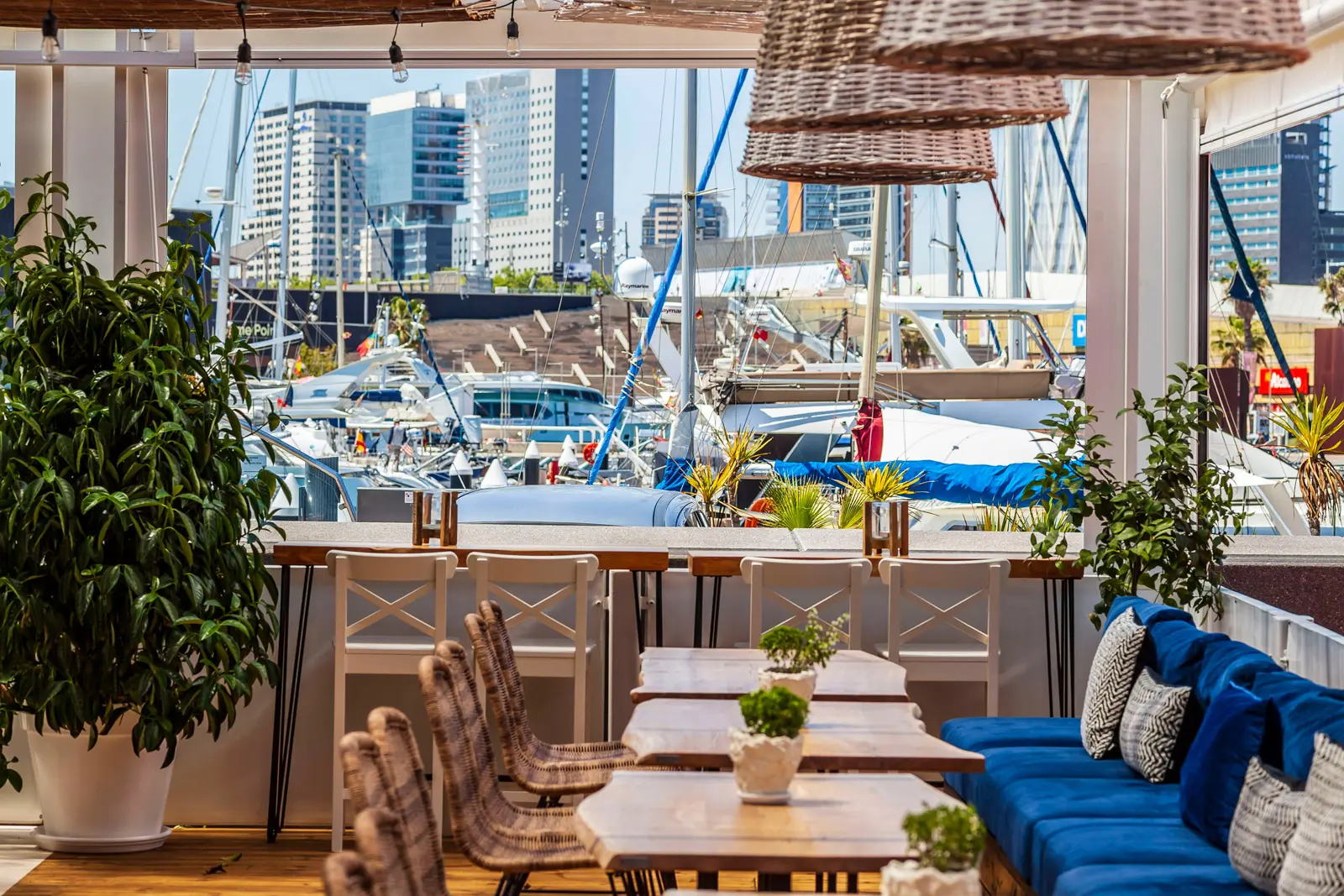 Outdoor dining terrace overlooking Marina Port Vell in Barcelona, with views of moored yachts