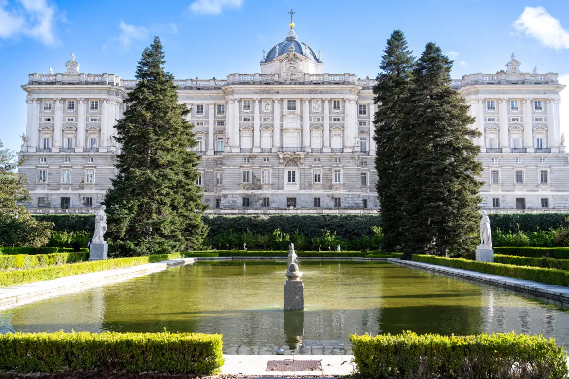 The Palacio Real (Royal Palace) of Madrid viewed from the Sabatini Gardens, with reflecting pool, statues, and lush hedges