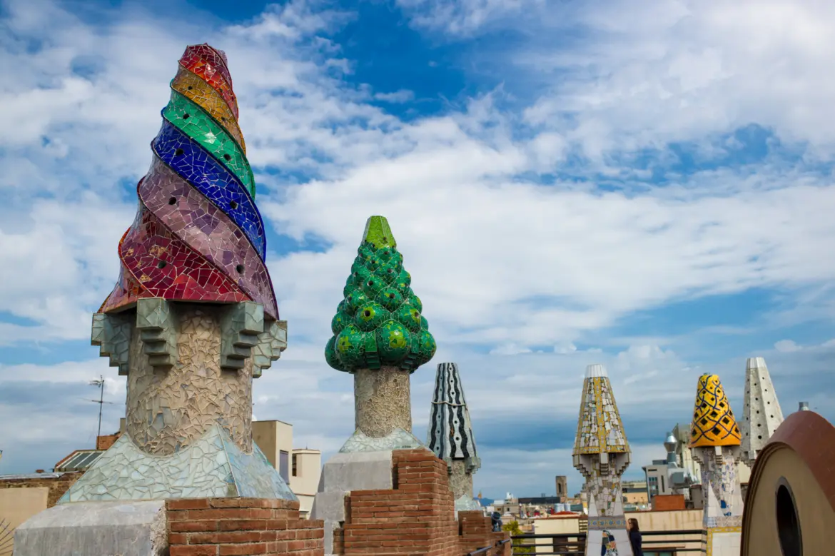 The rooftop of Palau Güell in Barcelona, with twenty mosaic-covered chimneys rising like coral towers — Gaudí's whimsical early masterpiece steps from La Rambla in the Raval district