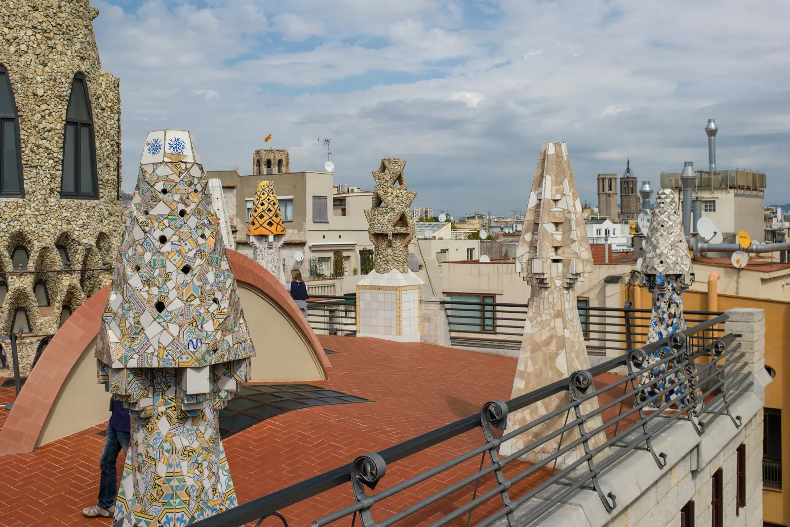 Close-up of Palau Güell's rooftop in Barcelona, showing the intricate trencadís mosaic work on Gaudí's fantastical chimneys with their swirling patterns of broken tile