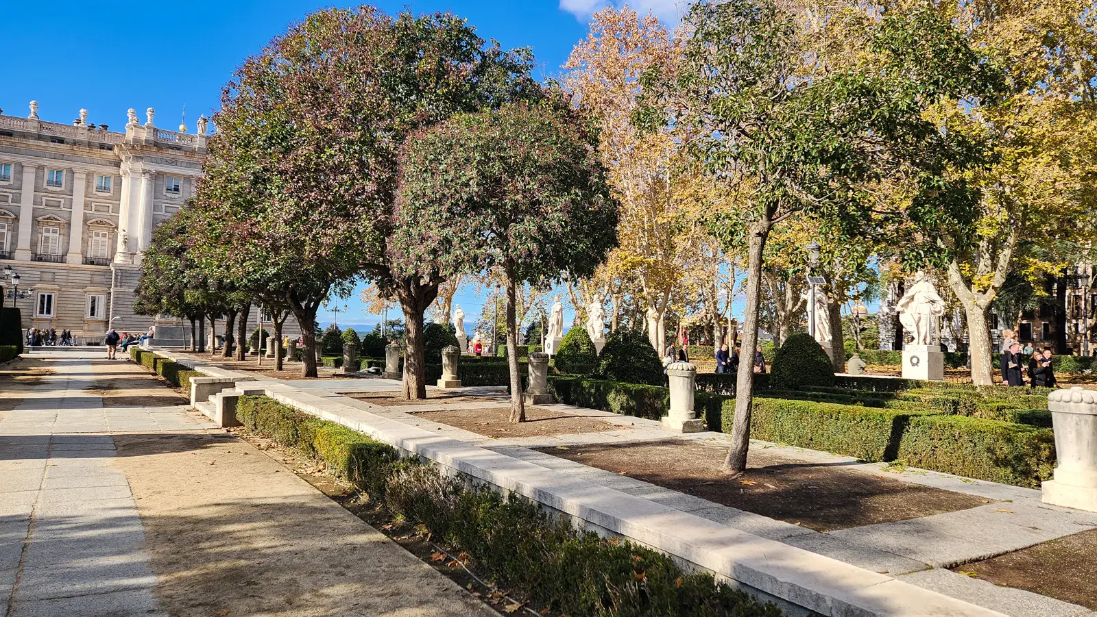 Plaza de Oriente at golden hour in Madrid with warm amber light on statues and gardens