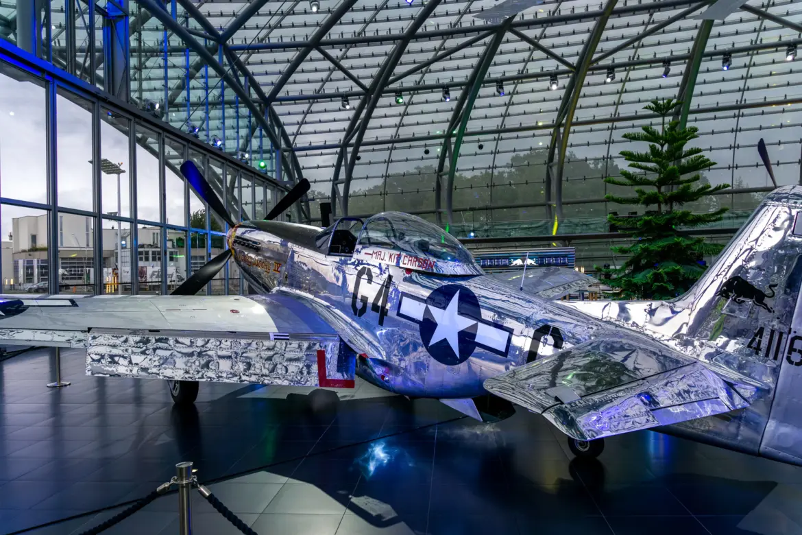 Polished P-51D Mustang in the Kit Carson Nooky Booky IV livery displayed inside Red Bull Hangar-7 in Salzburg, Austria