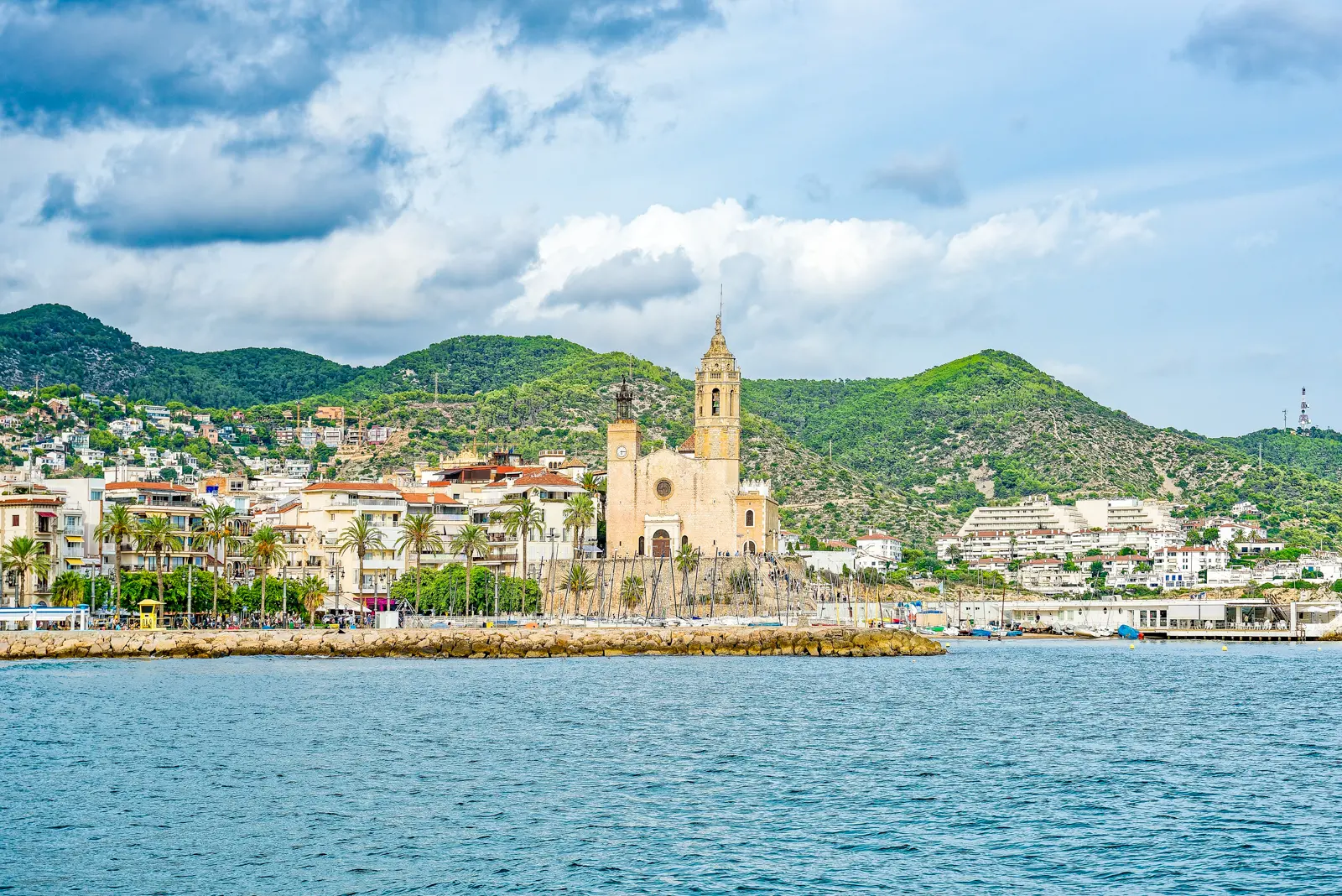 The charming coastal town of Sitges south of Barcelona, with whitewashed houses, blue shutters, bougainvillea-filled alleys, and the sparkling Mediterranean stretching to the horizon