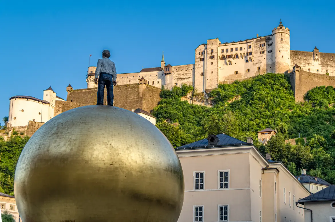 Sphaera sculpture by Stephan Balkenhol in Salzburg, Austria, with Hohensalzburg Fortress rising behind it on a summer day