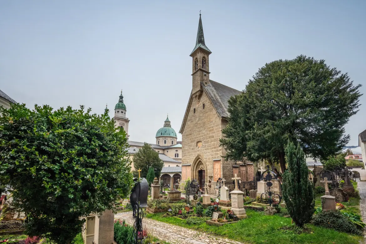 St. Margaret's Chapel in St. Peter's Cemetery in Salzburg with the green-domed towers of Salzburg Cathedral visible behind