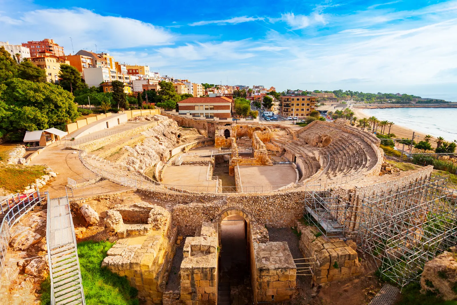 The 2nd-century Roman amphitheater in Tarragona perched above the sparkling Mediterranean, where gladiators once battled and ancient stones now watch the waves roll in after 2,000 years