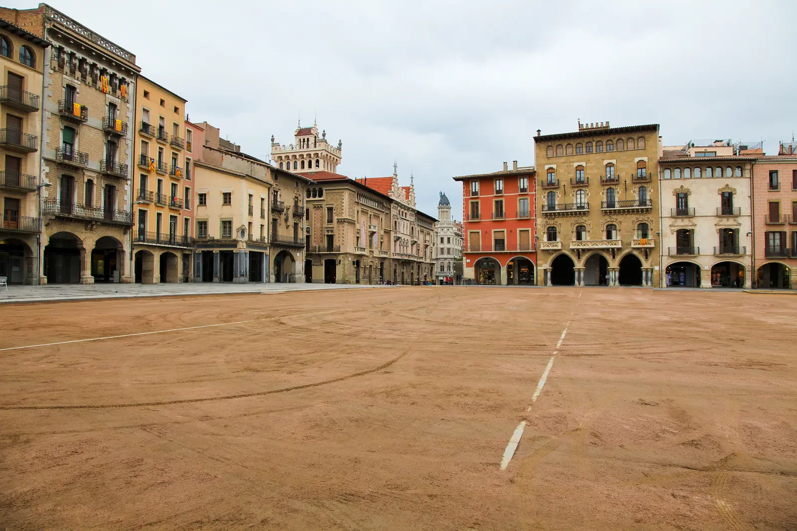 The porticoed Plaça Major in Vic transformed by the weekly market into a vibrant tapestry of local produce, cured meats, Catalan spices, and artisanal goods under the arches