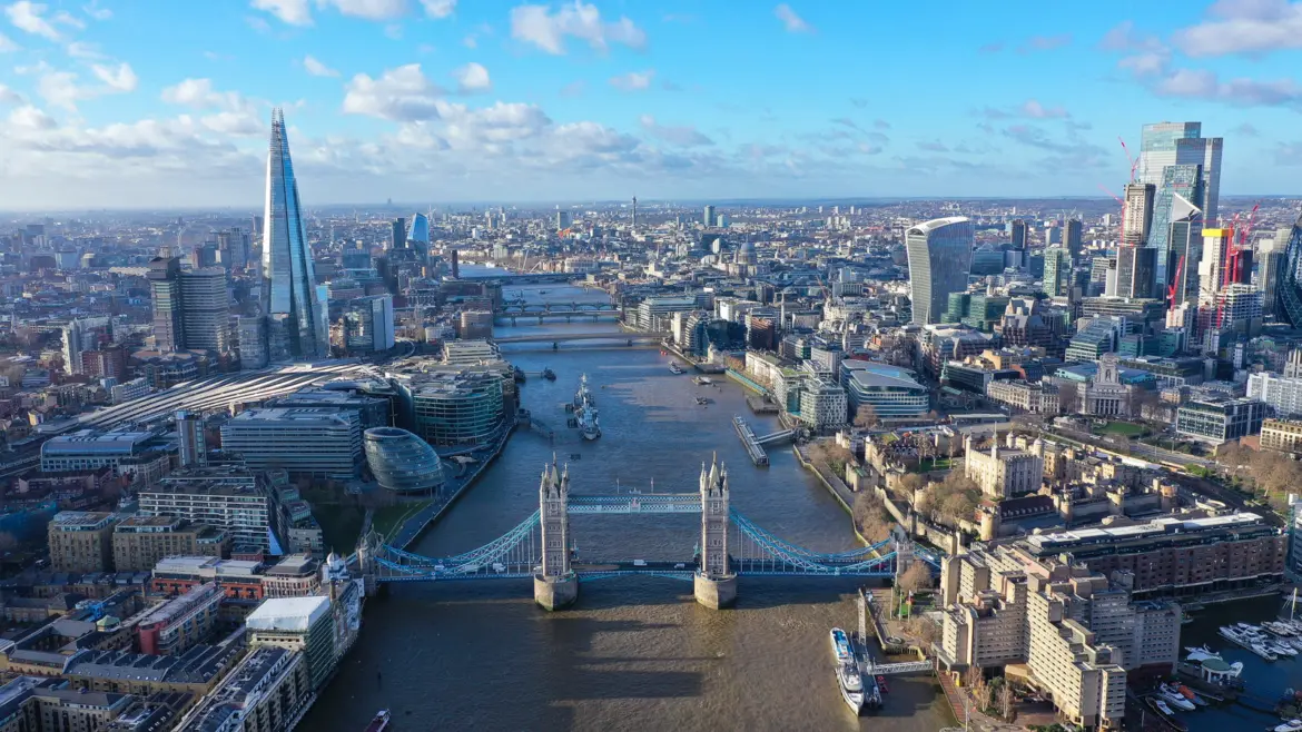 Aerial view of the River Thames flowing through London, featuring Tower Bridge, The Shard, and the evolving London skyline surrounding one of the city's most historic and defining landmarks